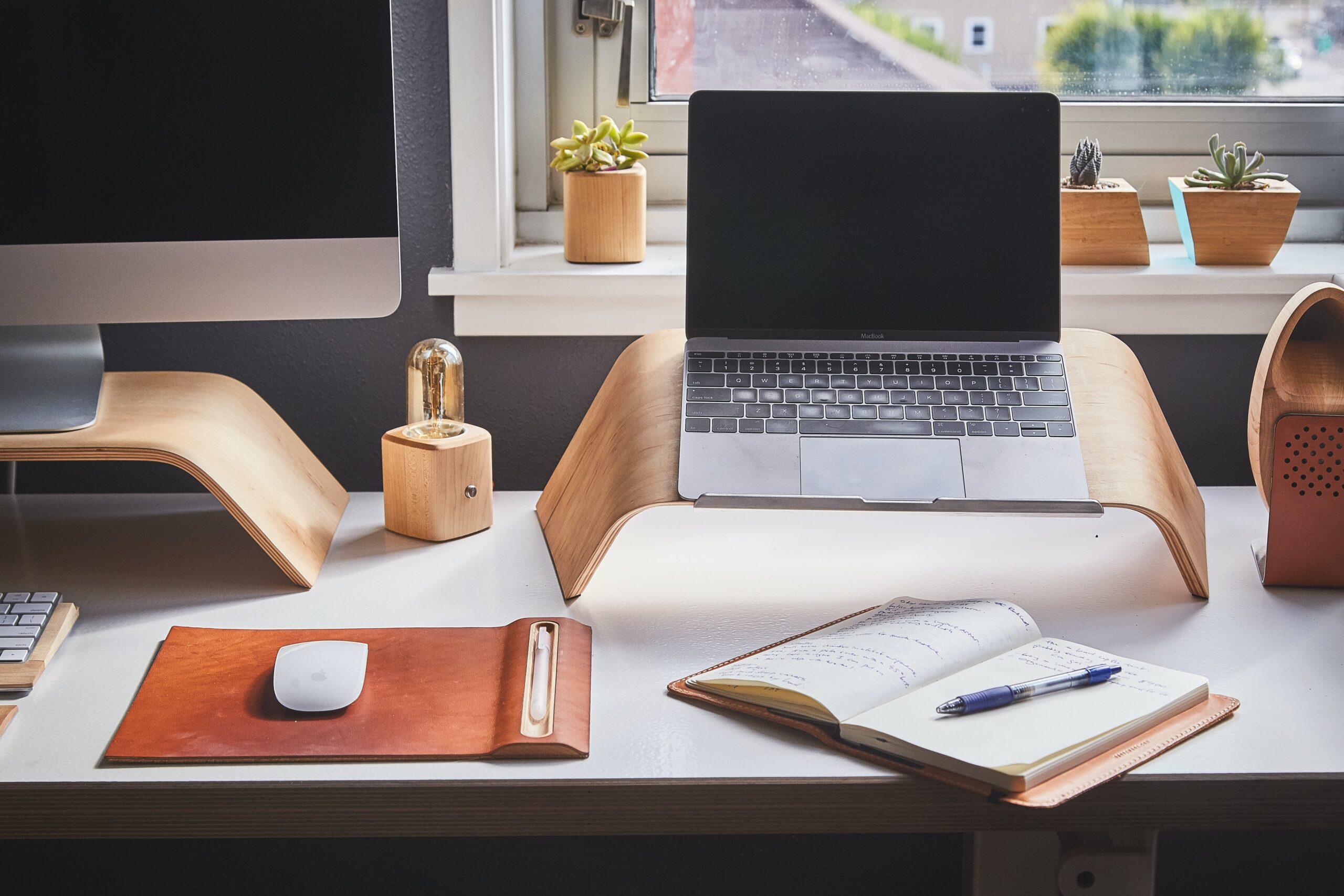 laptop, desktop computer, and a notebook atop a desk